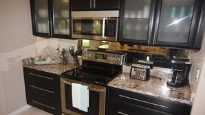 A modern kitchen with dark cabinetry, stainless steel appliances, and a granite countertop. - Secret Escape (Rotonda West)