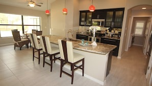 A modern kitchen with dark cabinets, a granite countertop, and a central island with bar stools. - Secret Escape (Rotonda West)