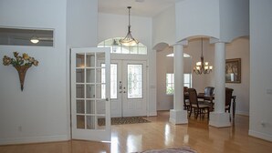 A spacious interior with a wooden floor, a dining area with a chandelier, and a large door with glass panels. - Amazing Lagoon (Rotonda West)