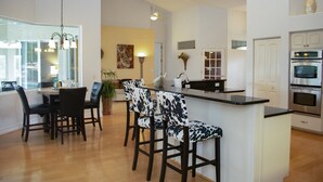 A modern kitchen with a central island, dining area with chairs, and built-in appliances. - Amazing Lagoon (Rotonda West)
