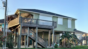 A two-story house with a balcony and a covered porch. - LOS PELICANOS - 2 bedroom, Gulf View, Palapa Bar on deck!! (Crystal Beach)