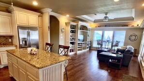 A spacious kitchen with a large island, wooden flooring, and built-in cabinetry. - LOS PELICANOS - 2 bedroom, Gulf View, Palapa Bar on deck!! (Crystal Beach)
