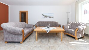 A living room with a wooden coffee table, two grey sofas, and a painting on the wall. - Apartment "below" - "House Passat" (Neuharlingersiel)