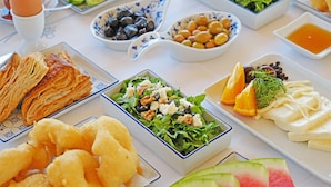A table with various dishes including salads, cheese, and pastries. - Evreka Butik Otel (Bozcaada)
