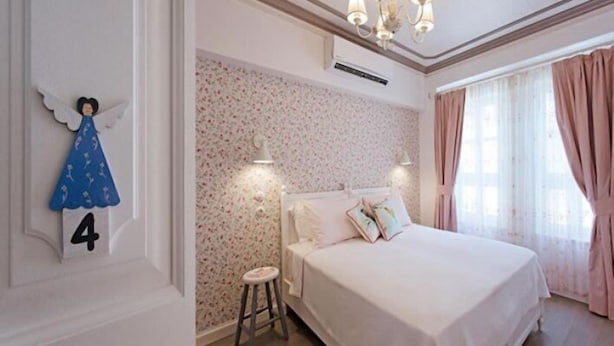 A bedroom with a large bed, a nightstand, a wall-mounted number '4', and a decorative angel figure. - Evreka Butik Otel (Bozcaada)