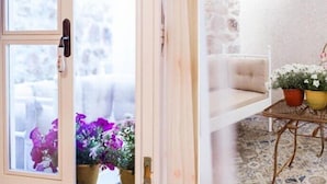 A room with a white sofa, a small table with potted plants, and a view of the outdoors through a window with a door handle. - Evreka Butik Otel (Bozcaada)