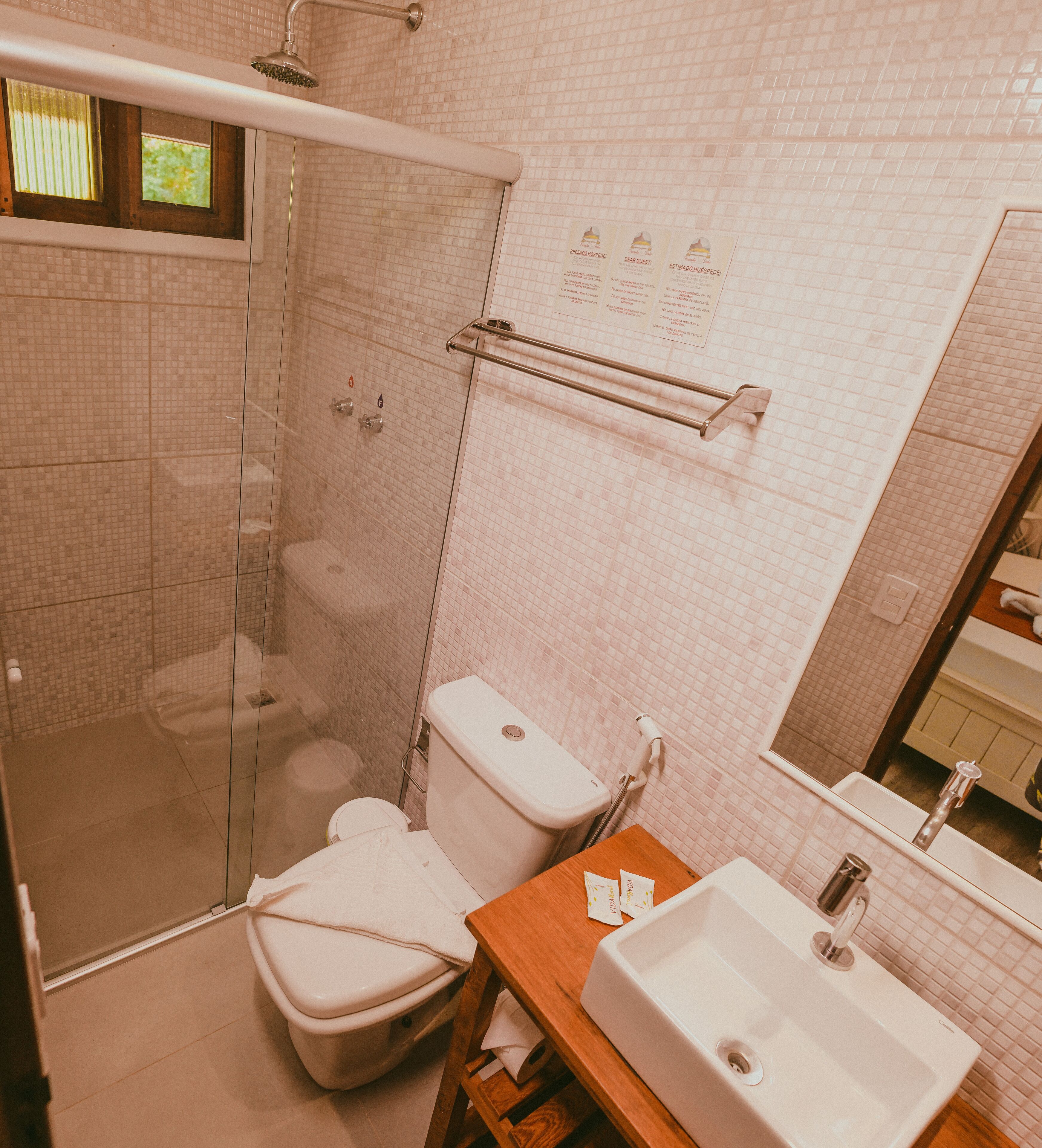 A bathroom with a glass-enclosed shower, a toilet, and a sink with a mirror.
