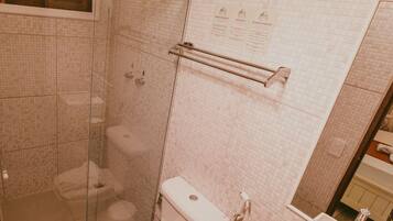A bathroom with a glass-enclosed shower, a toilet, and a sink with a mirror.