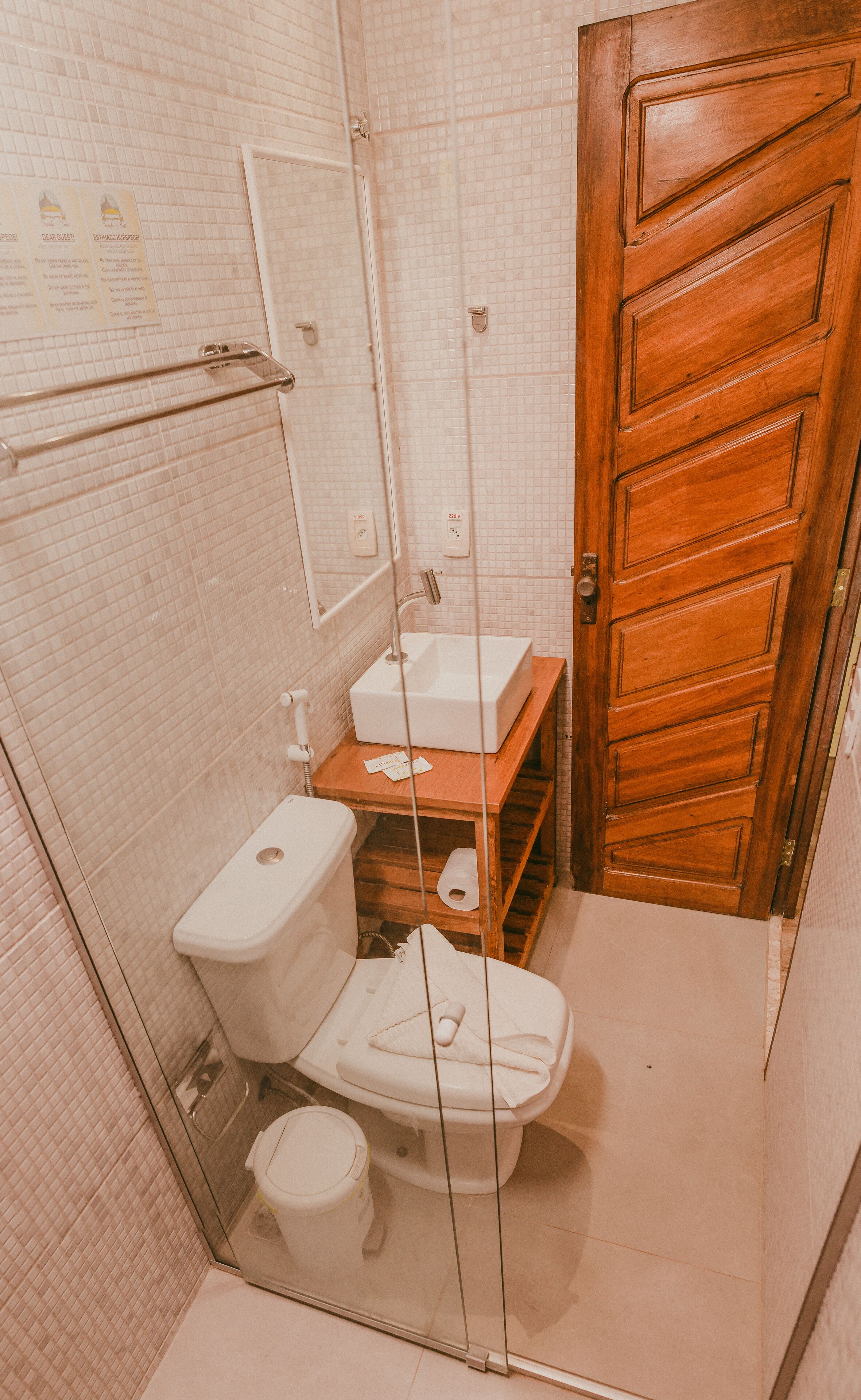 Ein kleines Badezimmer mit Toilette, Waschbecken und Holztür.