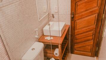 Ein kleines Badezimmer mit Toilette, Waschbecken und Holztür.