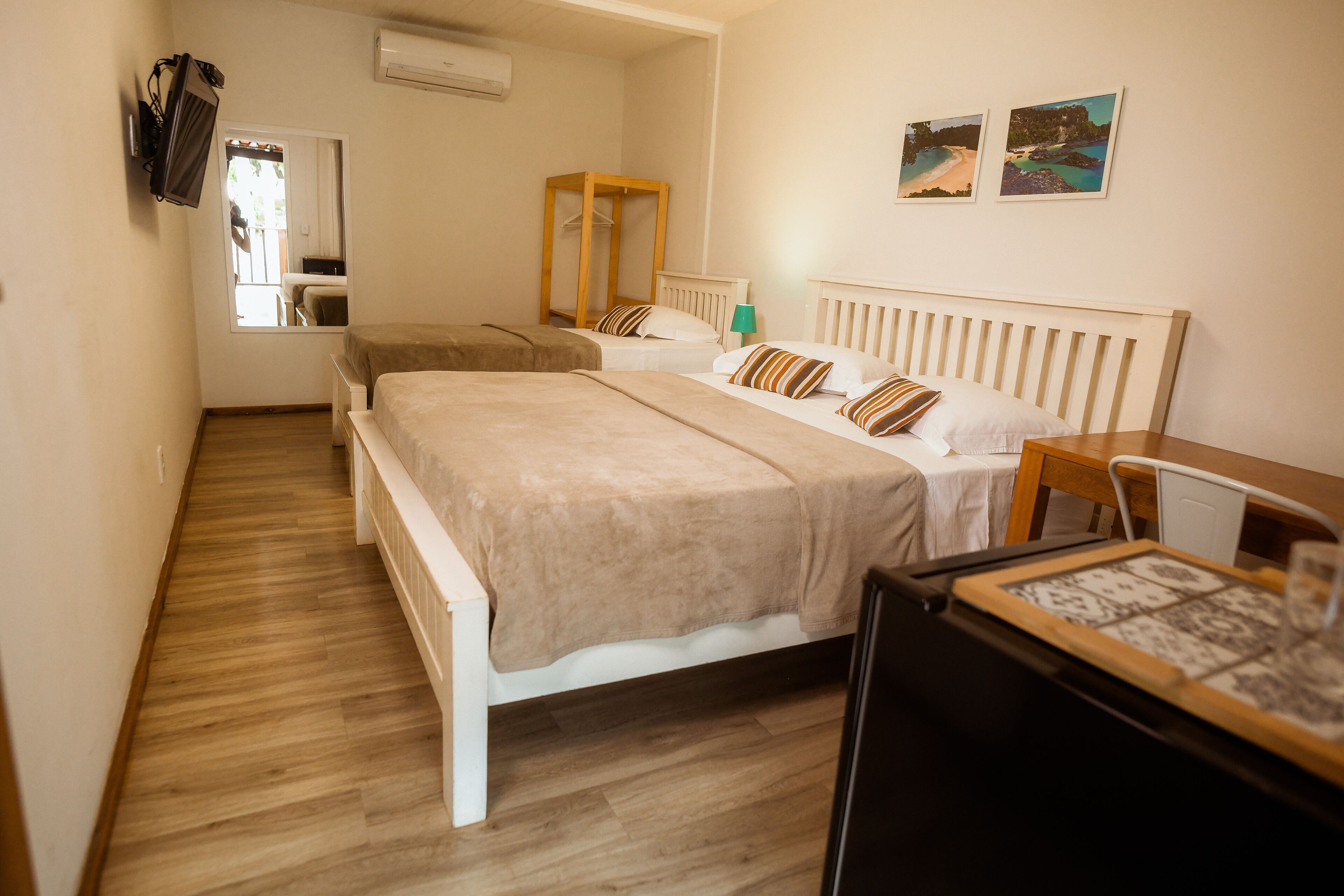 A bedroom with two beds, a wooden wardrobe, a desk, and a chair.