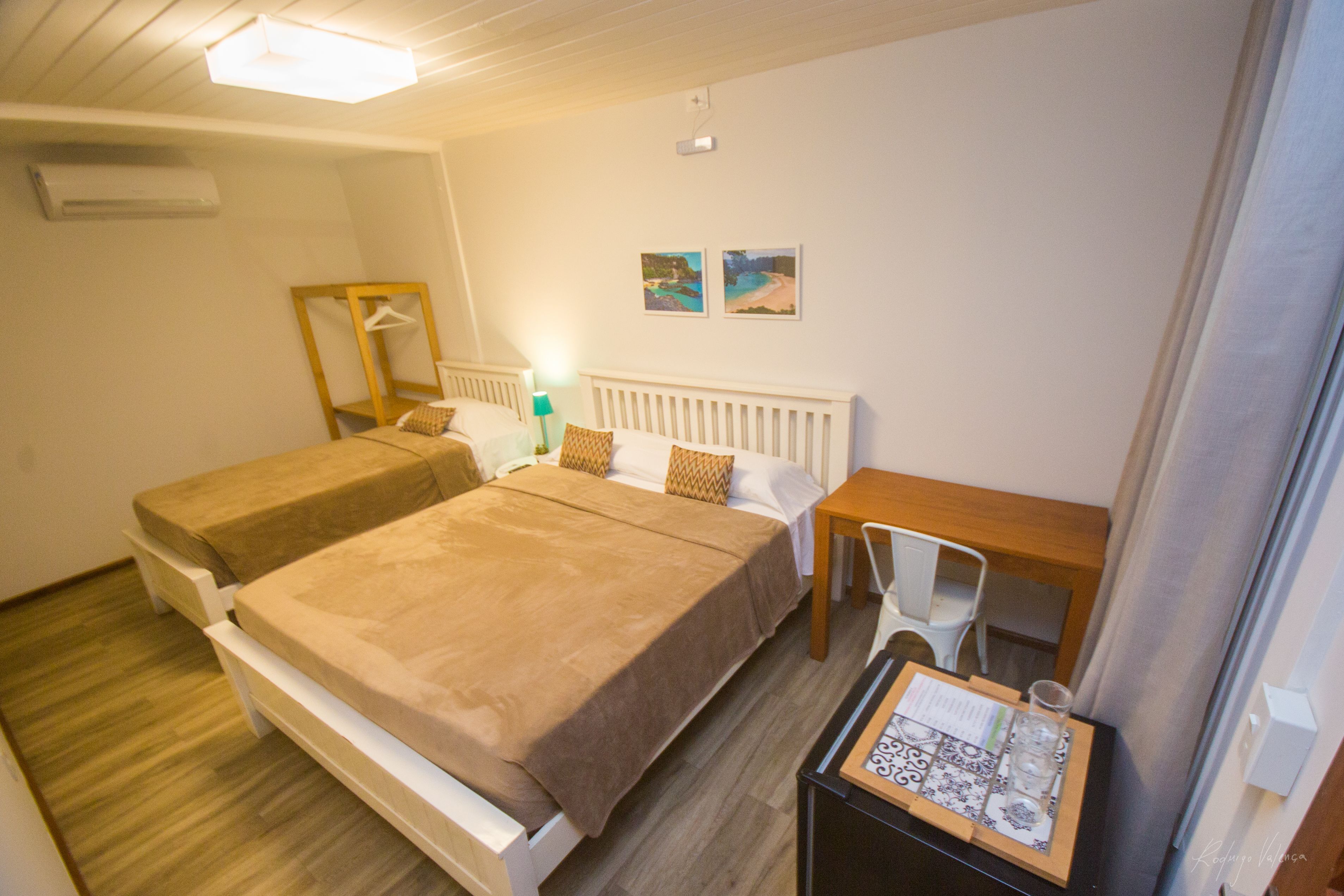 A hotel room with two beds, a small table, a chair, and a mirror.