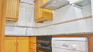 A kitchen with wooden cabinets, a built-in oven, and a white dishwasher.