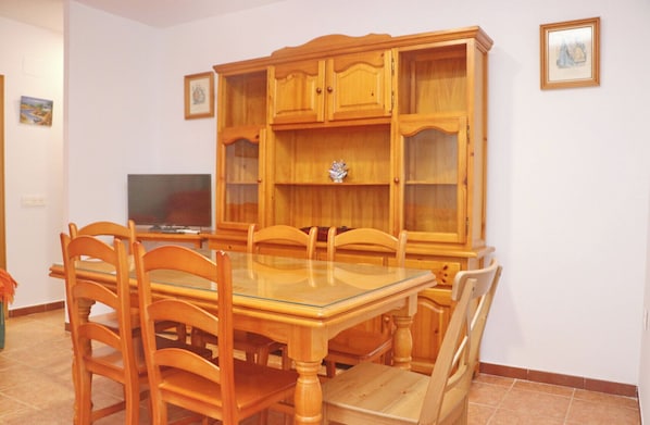 Un coin repas comprenant une table à plateau en verre, des chaises en bois et un buffet en bois doté de portes en verre.