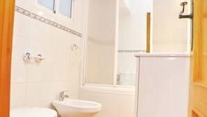 A bathroom with a toilet, bidet, and sink, all in white.