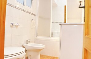 A bathroom with a toilet, bidet, and sink, all in white.