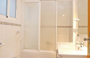 A bathroom with a shower enclosure, a sink, and a mirror.