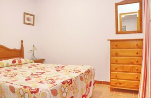A bedroom with a bed, dresser, nightstand, lamp, and a mirror.