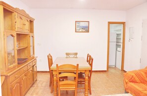 A dining area with a wooden table and chairs, a cabinet with glass doors, and a painting on the wall.