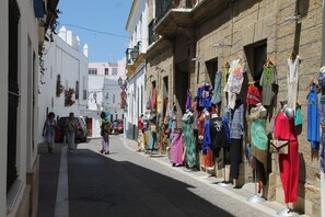 A narrow street with buildings on either side, displaying mannequins dressed in various outfits. - Central apartment for six people (CONIL DE LA FRONTERA)