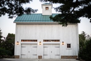 A large white building with a green roof, featuring two garage doors and a small tower-like structure on the roof. - Historic Cottage in the Heart of the Village (Granville)