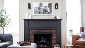 A living room with a fireplace, a framed picture above it, and two armchairs. - Historic Cottage in the Heart of the Village (Granville)