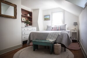 A bedroom with a bed, a dresser, a bench, a lamp, and a window. - Historic Cottage in the Heart of the Village (Granville)