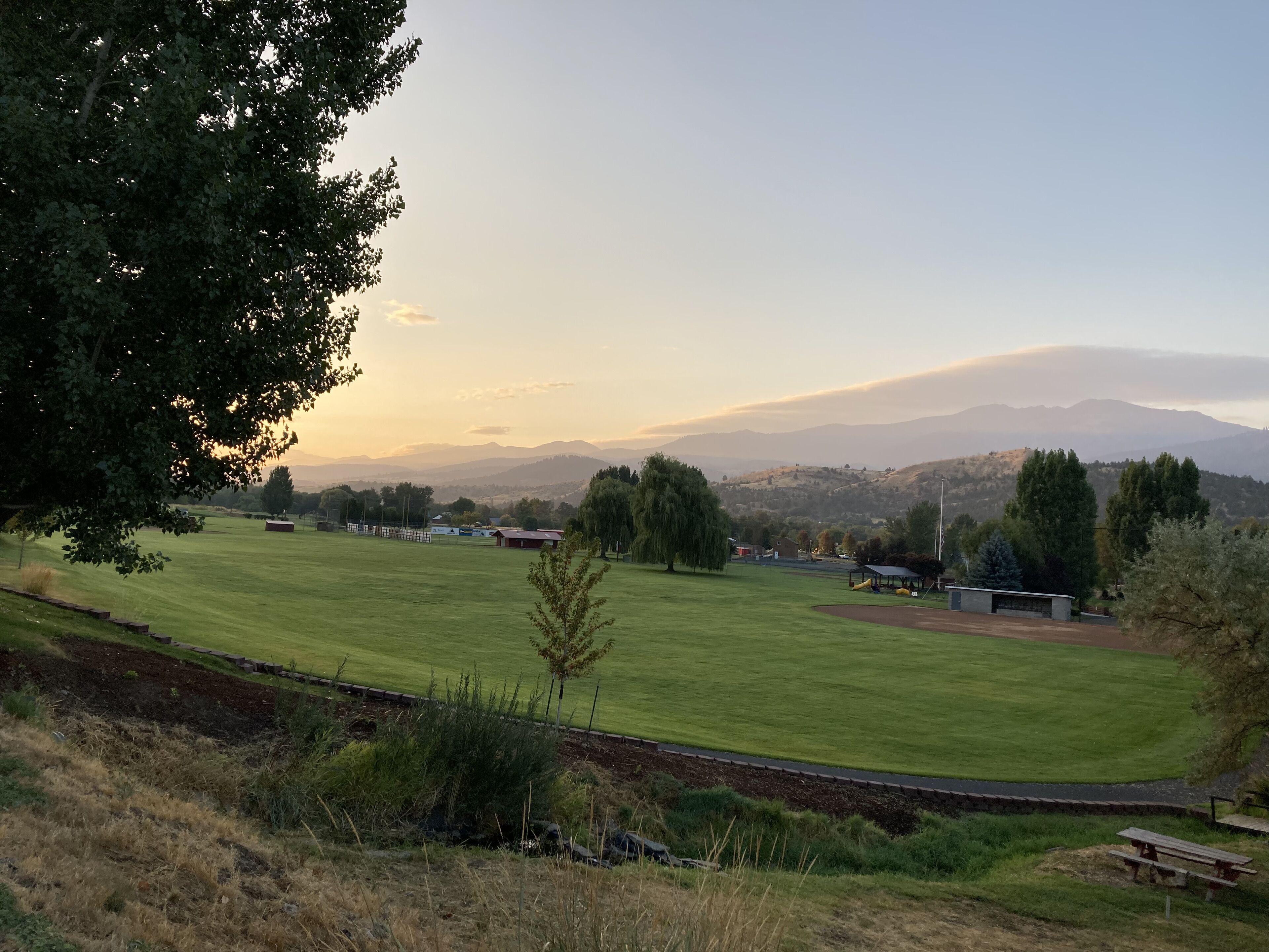A grassy field with a picnic area and a view of distant mountains.