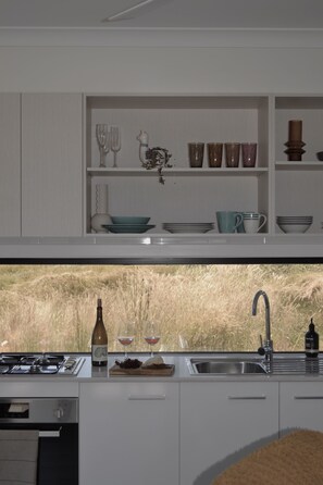 A modern kitchen with a large window, a sink, and a wine bottle.