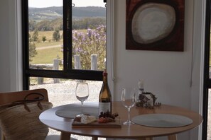 A dining table with a bottle of wine, two glasses, and a plate of food.