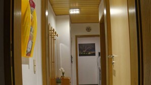 Un passadís amb portes de fusta, un sòl de marbre i una taula de recepció amb un ram de flors.