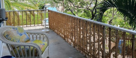 A balcony with wicker furniture and a bamboo fence.