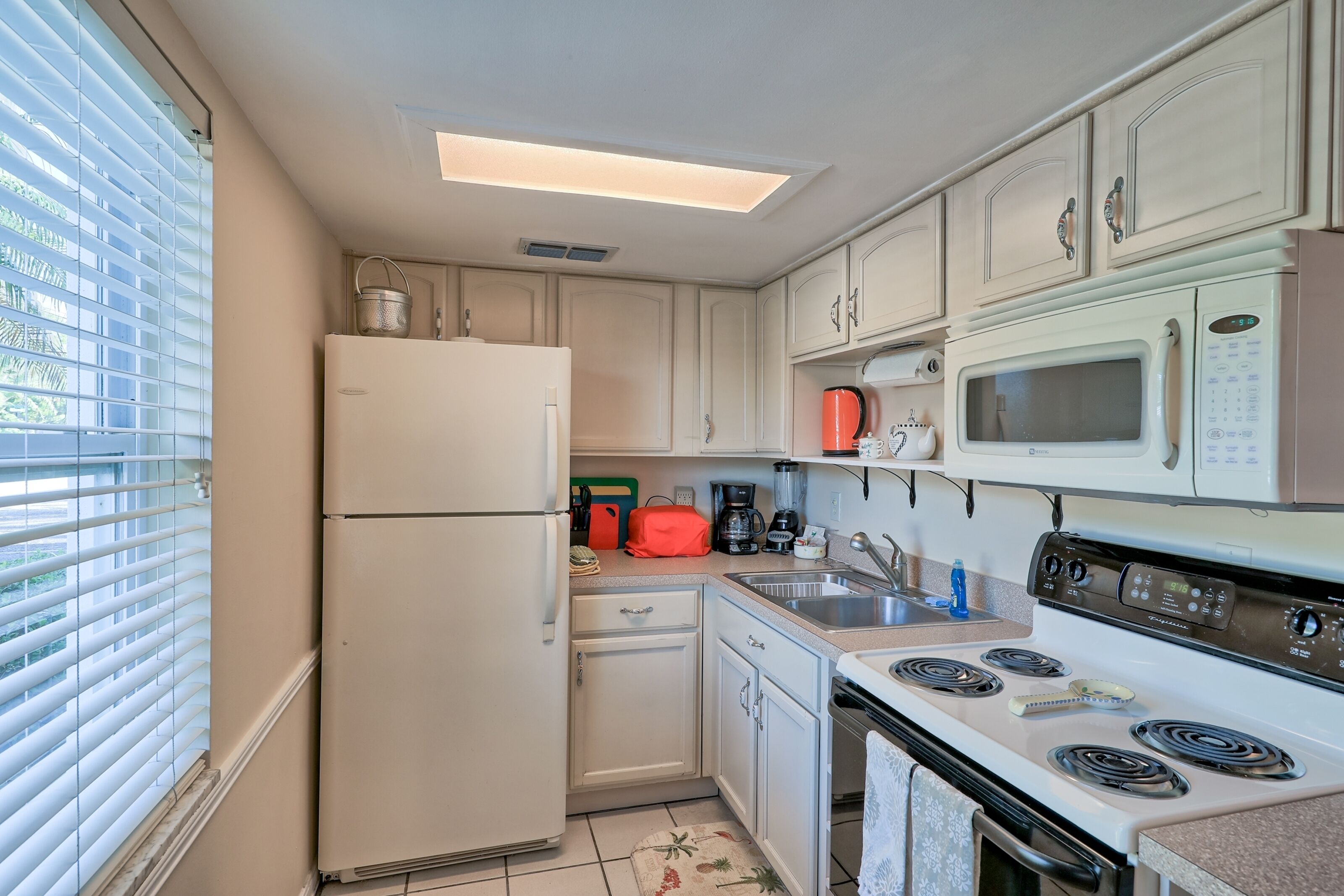 Una cocina compacta equipada con refrigerador, microondas, estufa y pileta.