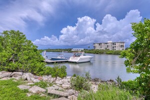 Un puerto deportivo con barcos amarrados, rodeado de vegetación y un edificio al fondo.
