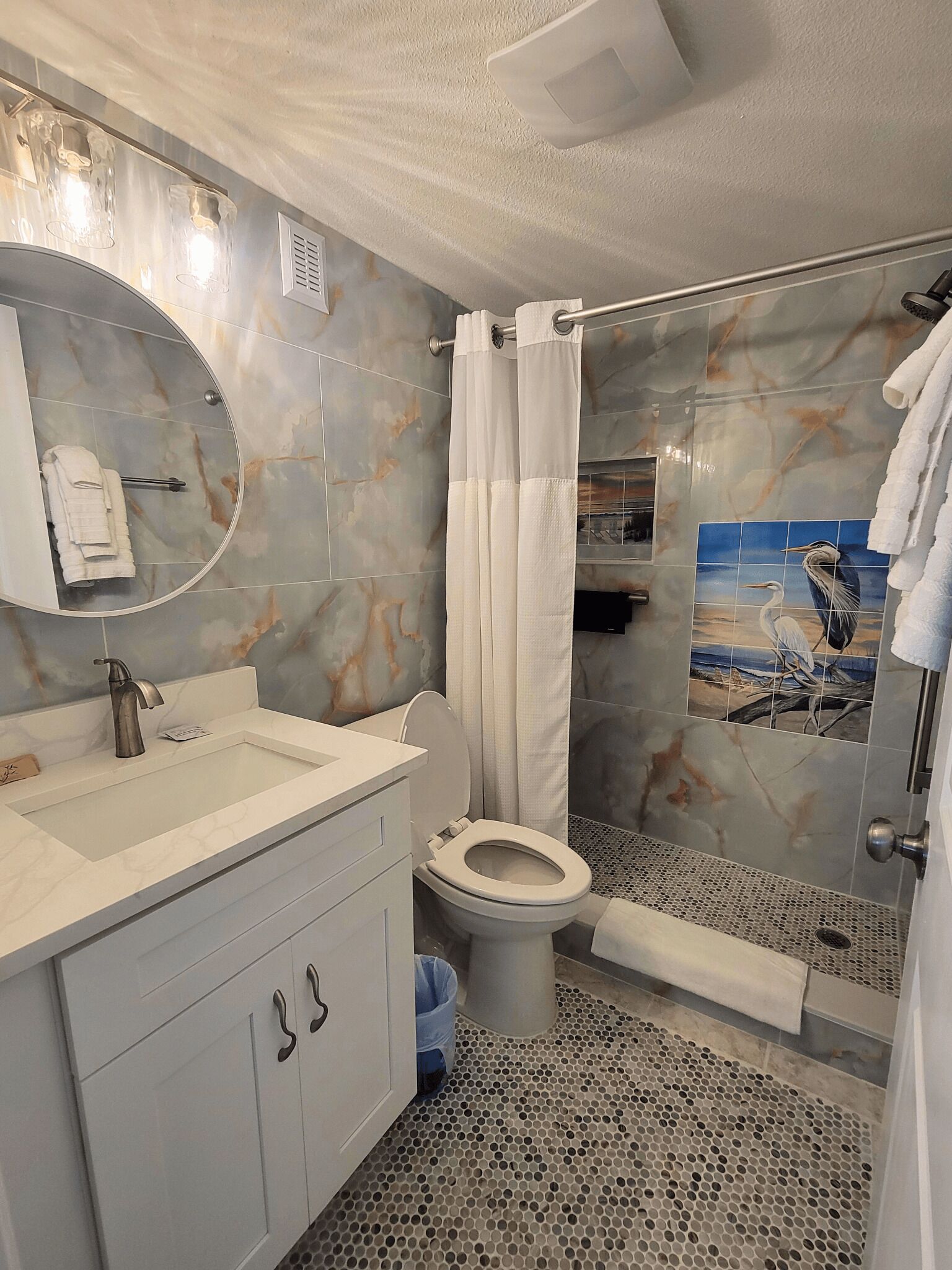 A bathroom with a marble vanity, a toilet, a shower with a glass door, and a towel rack.
