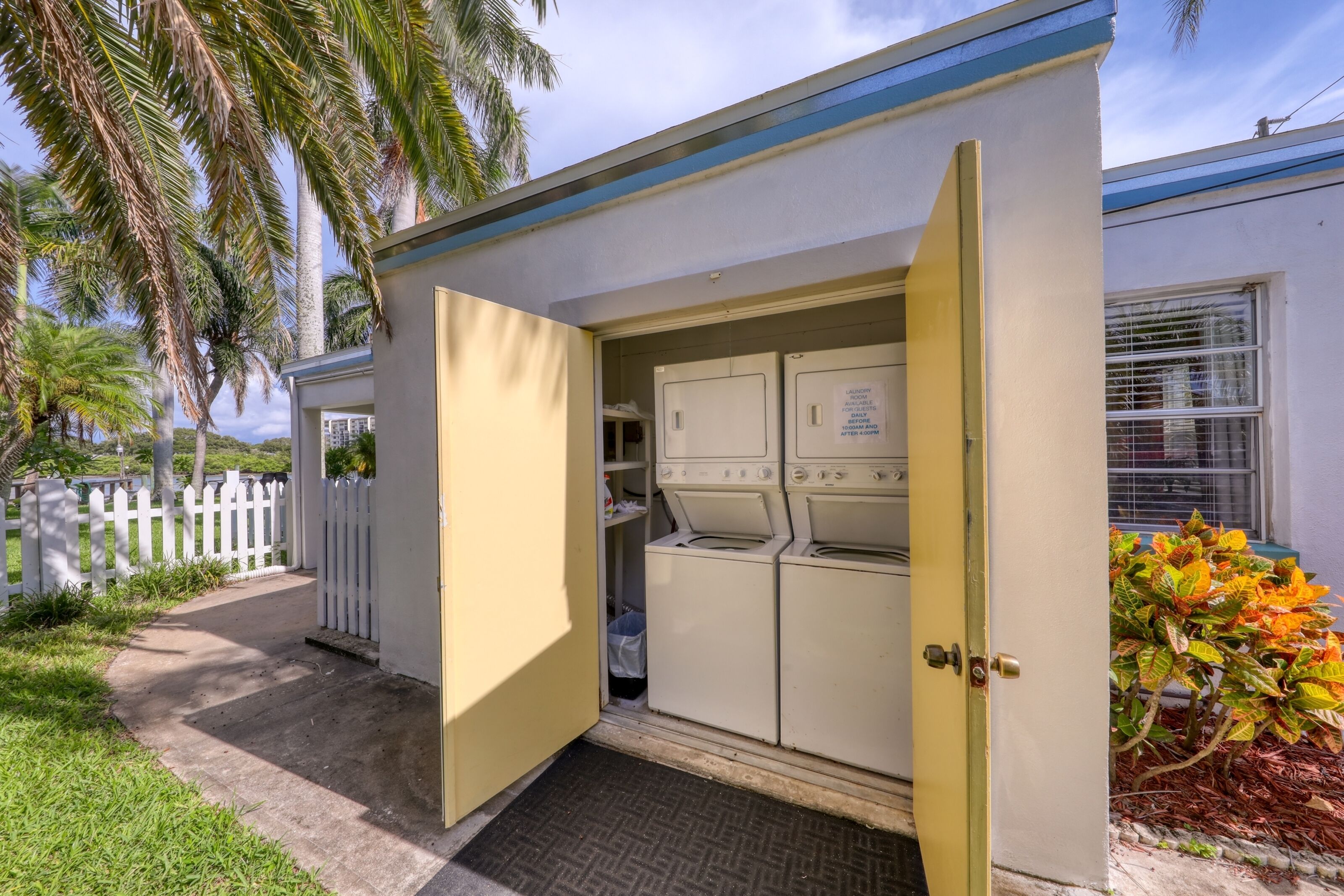 A laundry room with a door open, revealing washing machines and a small storage area.