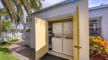 A laundry room with a door open, revealing washing machines and a small storage area.
