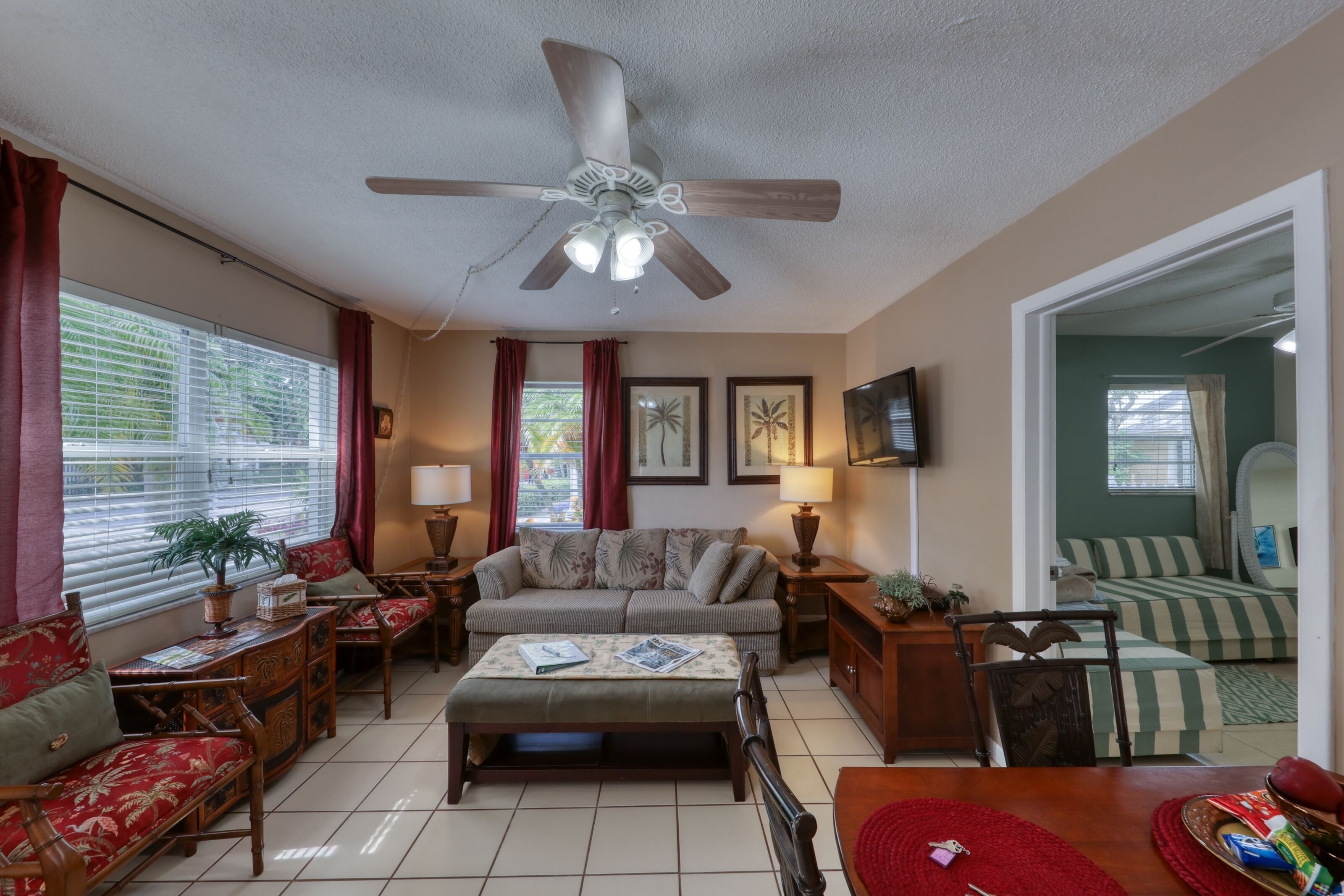 A living room with a sofa, a coffee table, a TV, and a ceiling fan.