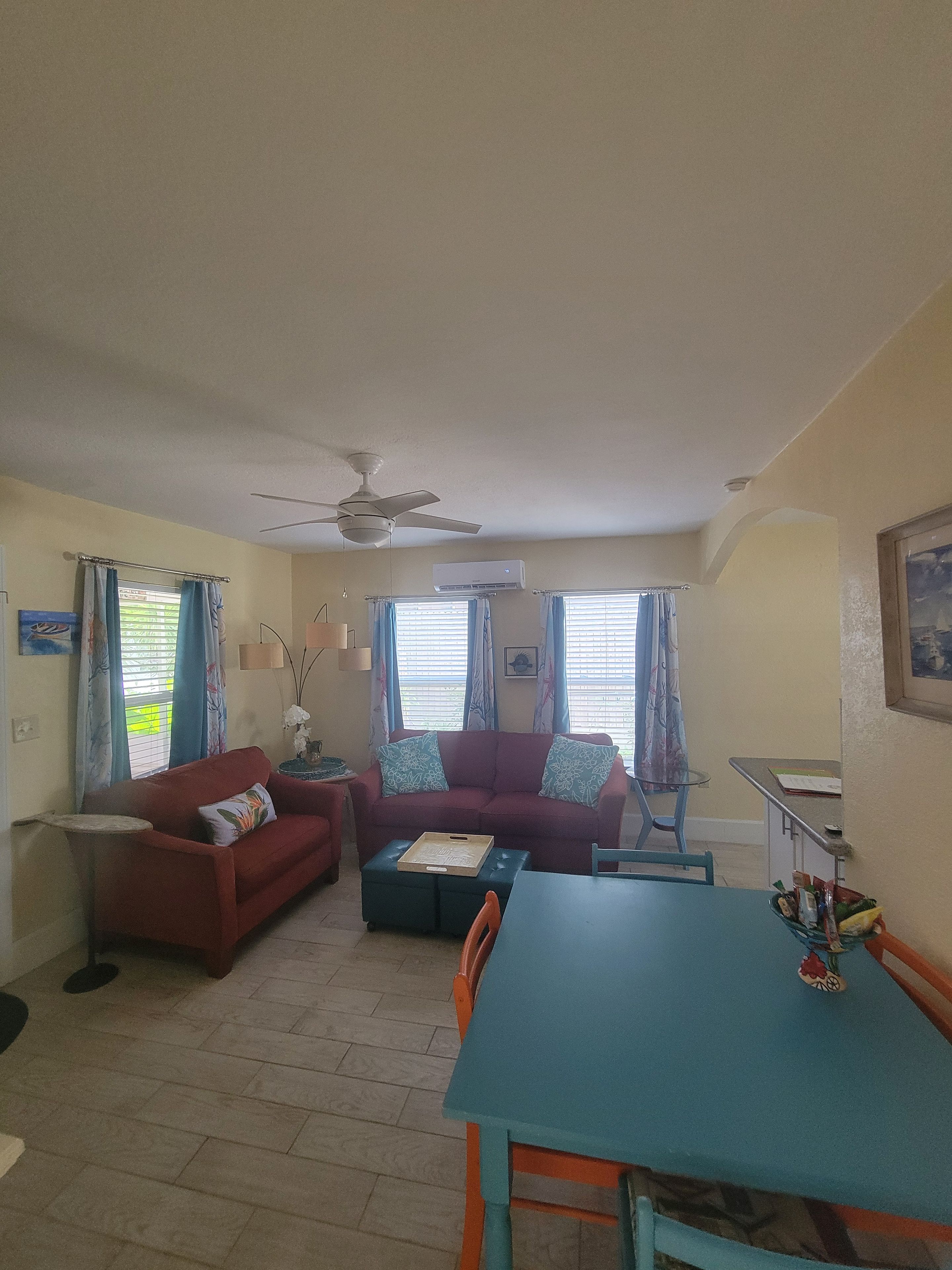 A living room with a red sofa, a blue table, and a ceiling fan.