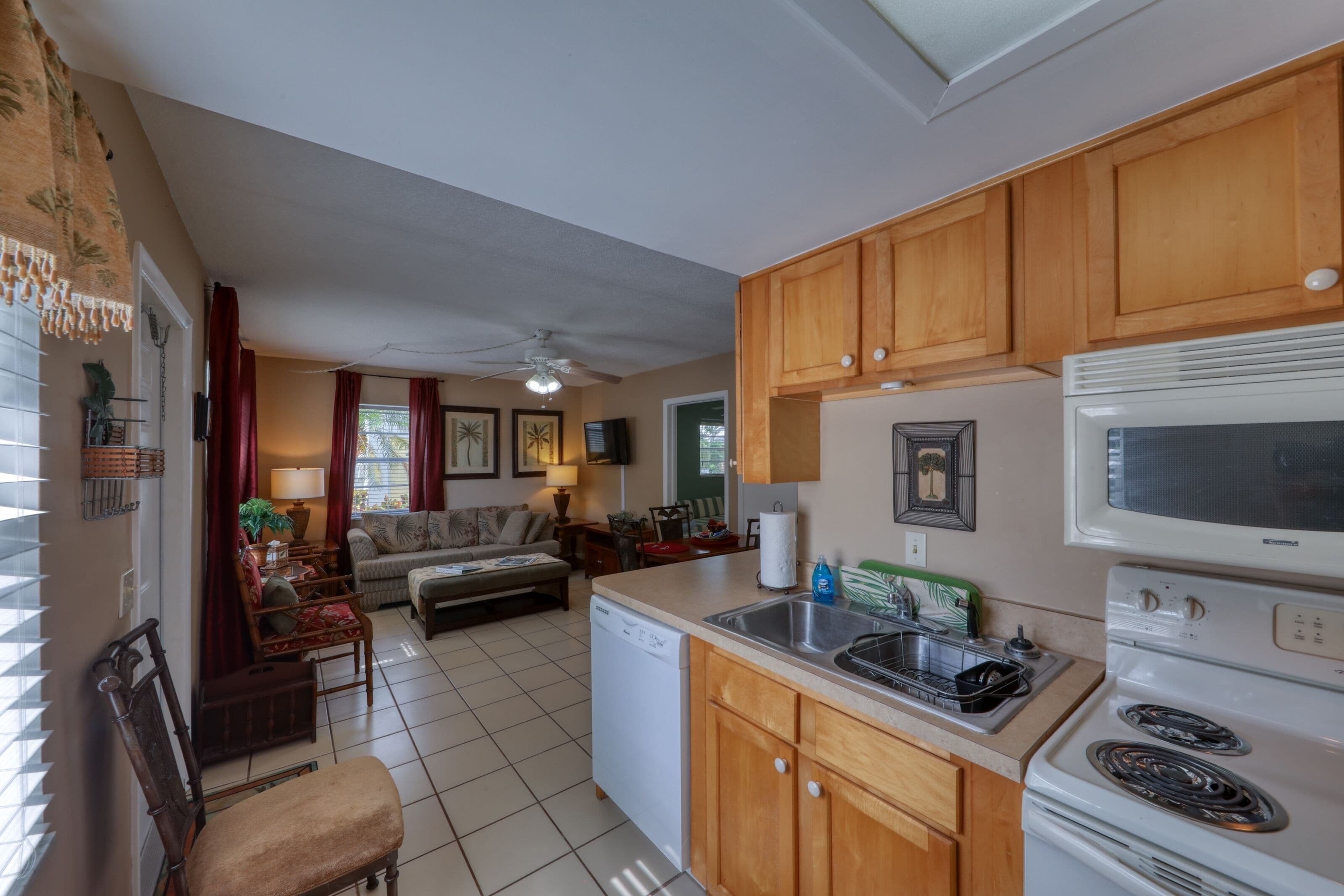 A compact kitchen with wooden cabinets, a white dishwasher, a microwave, and a stove.