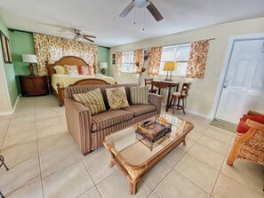 A room with a bed, a sofa, a dining table, and a ceiling fan. - BeachTrail Lodging (Indian Rocks Beach)