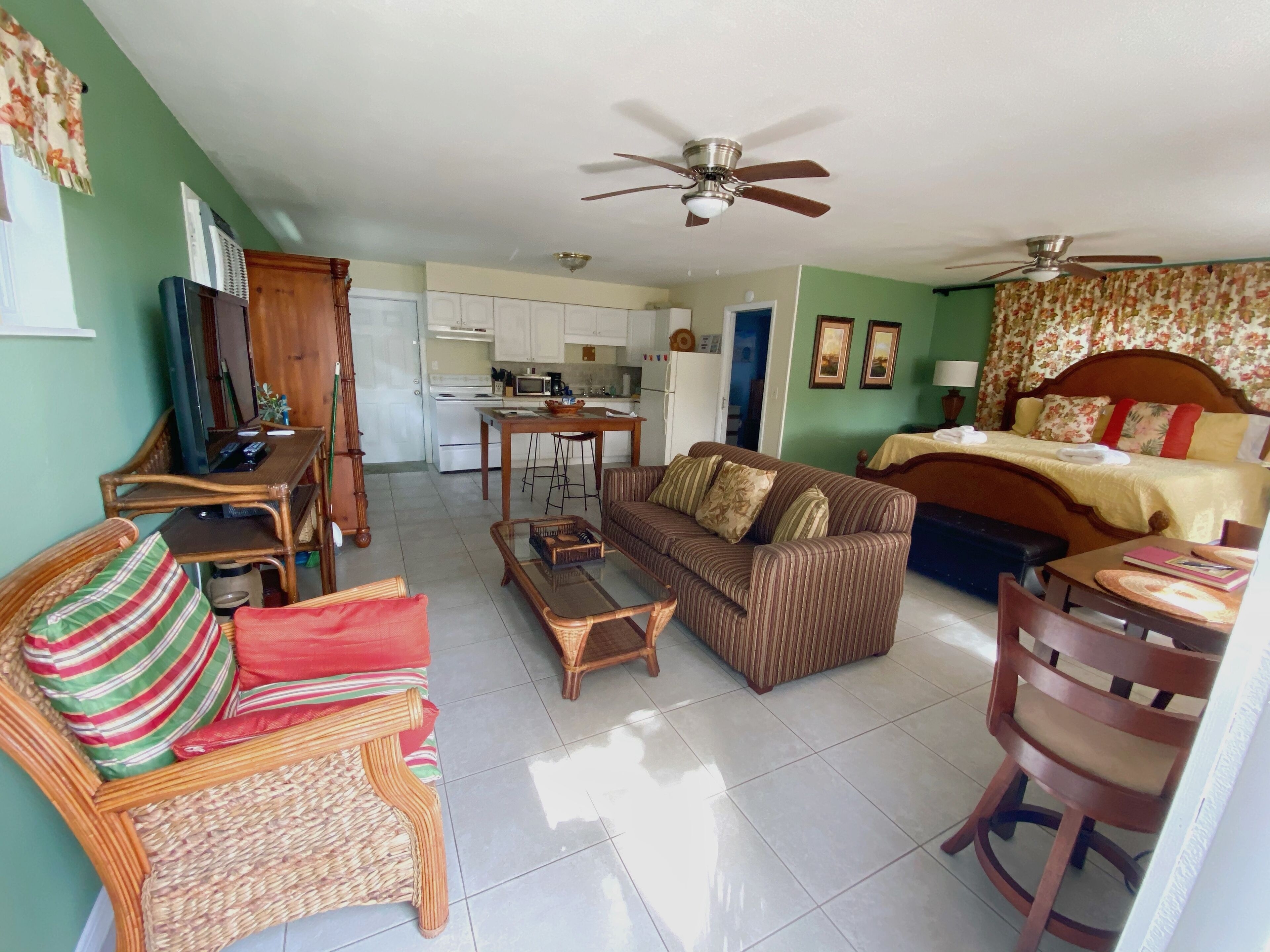 A compact living space with a sofa, a dining table, a kitchen area, and a bed.