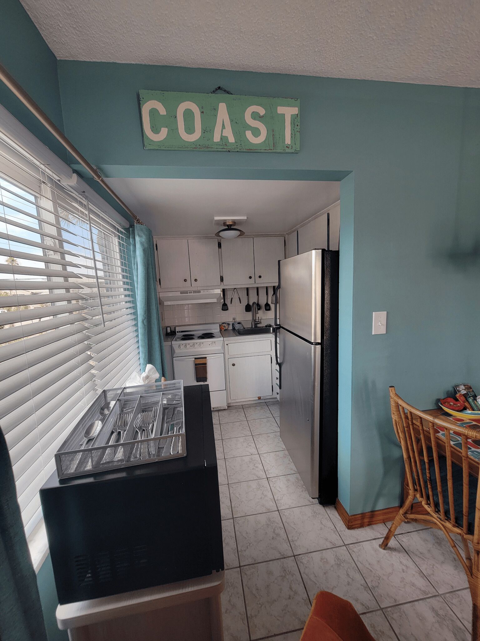 A kitchen with white cabinets, a black countertop, and a sign that reads "COAST".