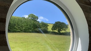 A view through a window of a grassy field with trees and a clear sky. - Luxurious home in secluded location with rural views just 5 mins drive to beach  (Torpoint)