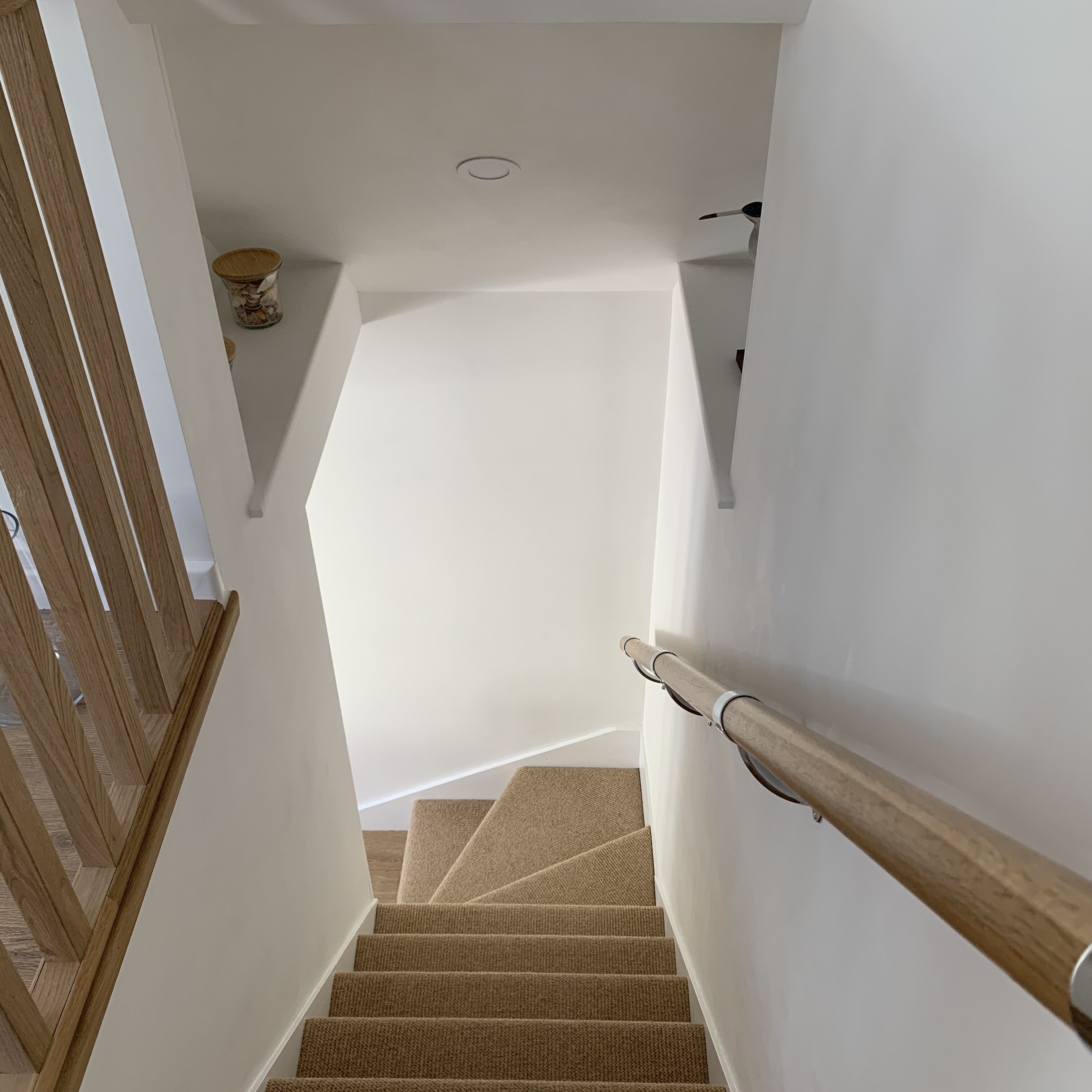 A staircase with wooden handrails and carpeted steps leading to a landing.