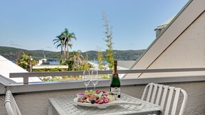 A balcony with a table set for a meal, a bottle of champagne, and two glasses. - Sunchaser - Iluka - Palm Beach (Palm Beach)