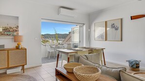 A modern living room with a balcony, a dining area, and a view of a pool and mountains. - Sunchaser - Iluka - Palm Beach (Palm Beach)
