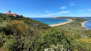 A coastal landscape with a lighthouse, beach, and hilly terrain. - Sunchaser - Iluka - Palm Beach (Palm Beach)
