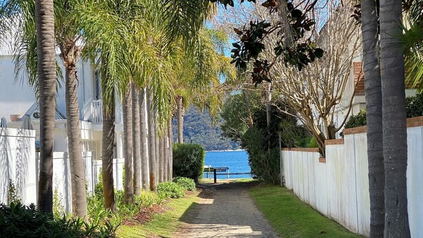A pathway lined with palm trees leading to a beach area. - Sunchaser - Iluka - Palm Beach (Palm Beach)