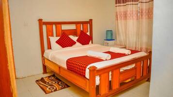 Una cama de madera con colcha a cuadros rojos y blancos, dos almohadas y una manta a juego.